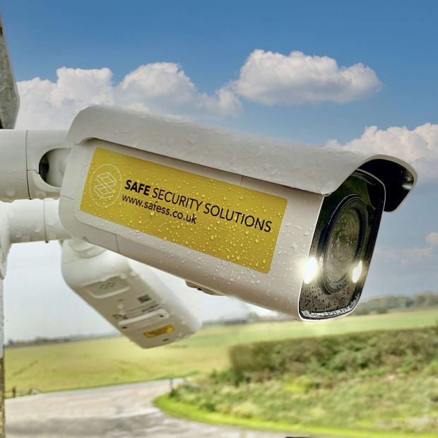 Safesitecam Smart AI Security Camera mounted on a wall in front of a landscape and clouds
