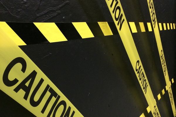 Yellow caution tape on a black wall.