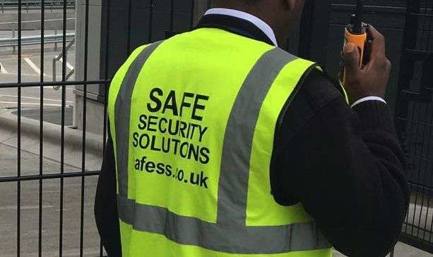 Close up image of security guard holiding a radio with Safe Security Solutions reflective vest