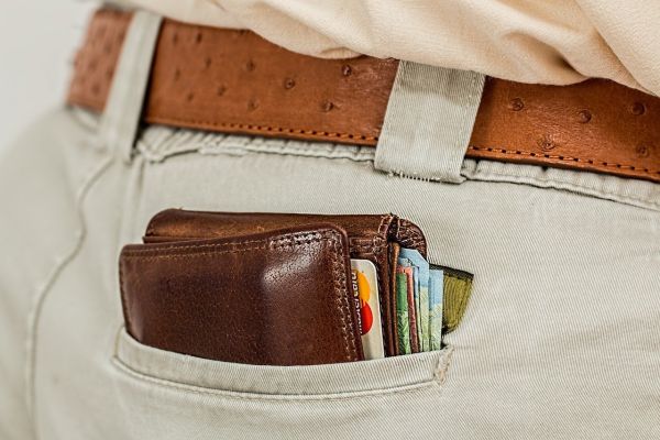 A bulging brown leather wallet in a mans back pocket.