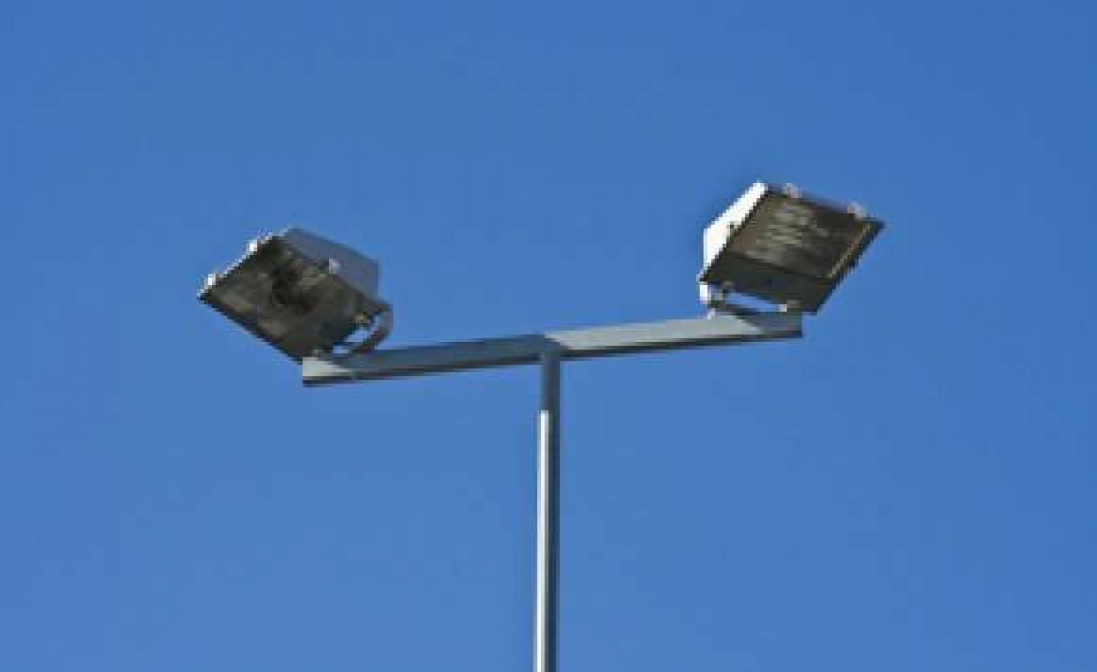 Two large floodlights on top of a T shaped pole.
