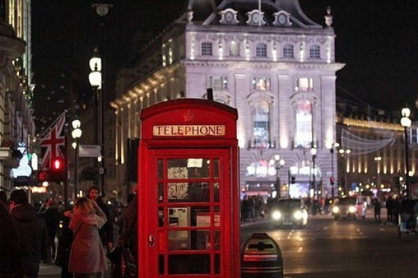 A red telephone box in front of an illuminated building