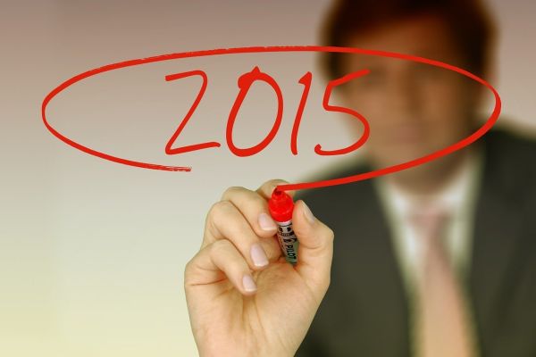 A man writing 2015 on a glass panel in red ink.
