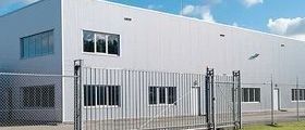 A large metal fence surrounding a large silver building