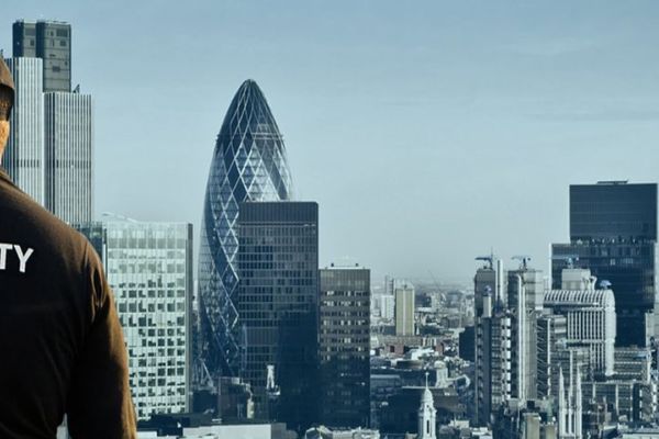A security guard talking on a radio looking out across the London skyline.