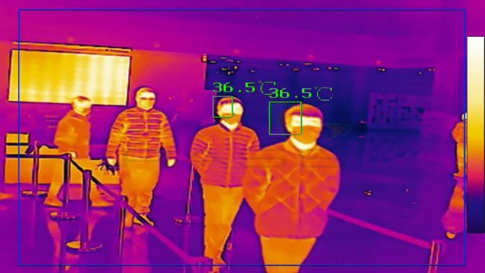 Thermal camera footage of four people in a queue being tracked by live camera footage.