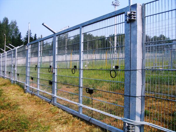 A perimeter fence with a motion sensor detector kit mounted to it.